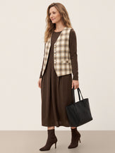 Model wearing a coffee wool pleated midi dress with a check linen vest
